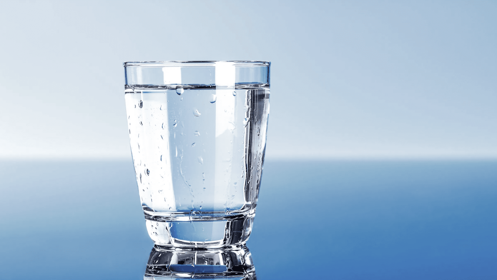 Full glass of water against a blue gradient background
